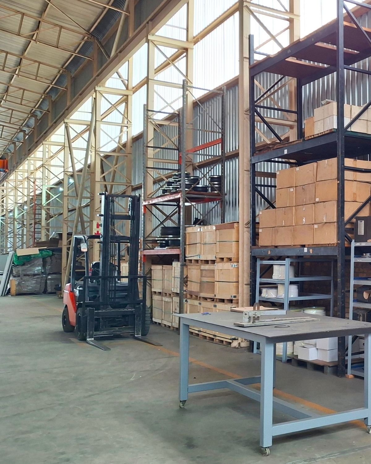 Sizwe Seals Industrial Warehouse and Equipment Storage Area Interior view of the Sizwe Seals industrial facility with warehouse racking, boxed components, a forklift and a mobile workbench in a clean workshop environment.